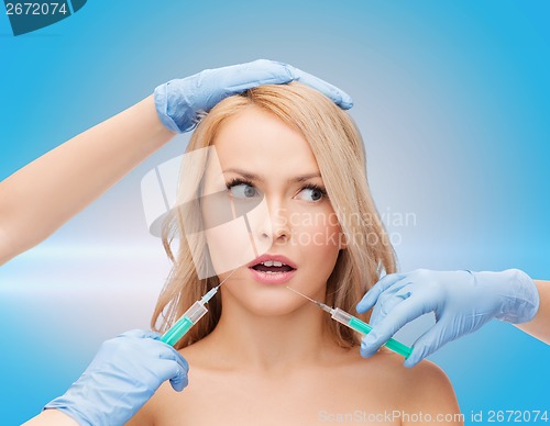 Image of woman face and beautician hands with syringes