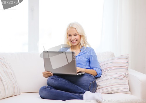 Image of smiling woman with laptop computer at home