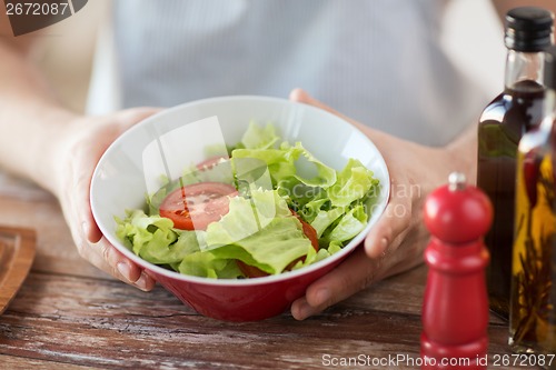 Image of close of male hand holding a bowl with salad