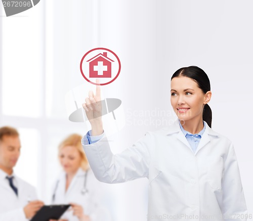 Image of smiling female doctor pointing to hospital sign