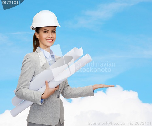Image of smiling architect in white helmet with blueprints