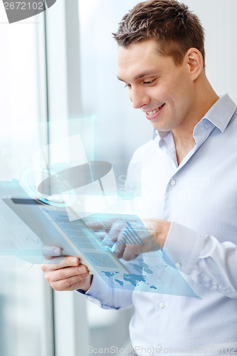 Image of smiling businessman with tablet pc in office