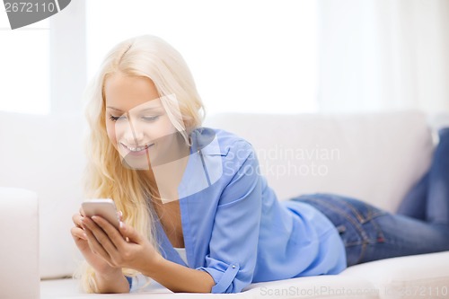 Image of smiling woman with smartphone at home