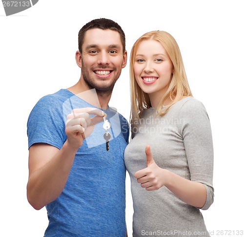 Image of smiling couple holding keys and showing thumbs up