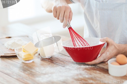 Image of close up of male hand whisking something in a bowl