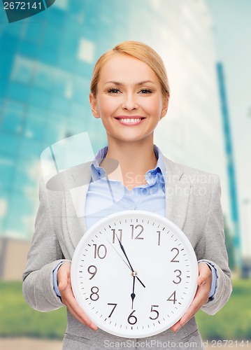 Image of smiling businesswoman with wall clock