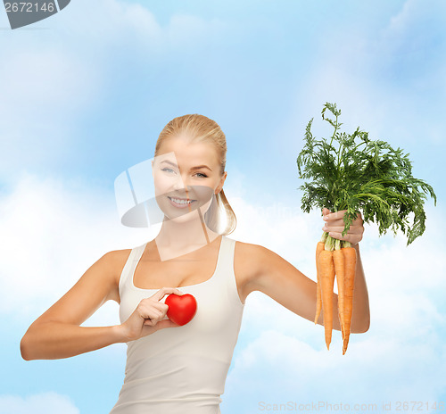 Image of smiling woman holding heart symbol and carrots