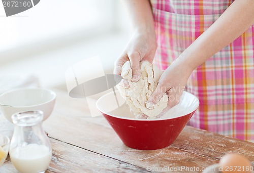 Image of close up of female hands kneading dough at home