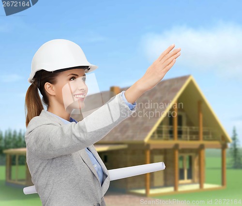 Image of smiling architect in white helmet with blueprints