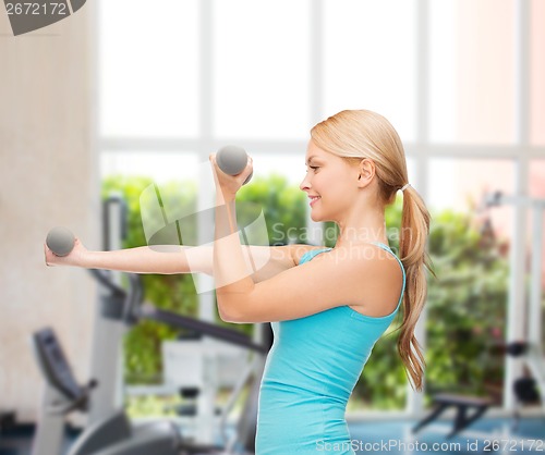 Image of young sporty woman with light dumbbells