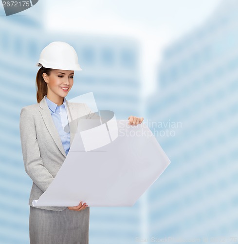 Image of smiling architect in white helmet with blueprints