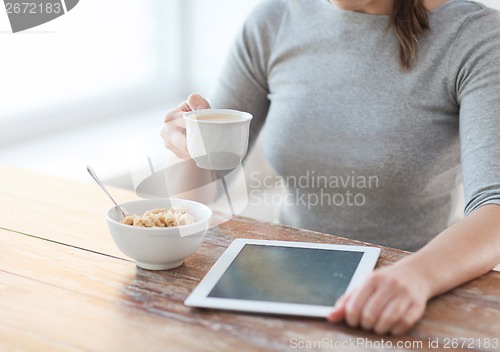 Image of woman drinking coffee and using tablet pc