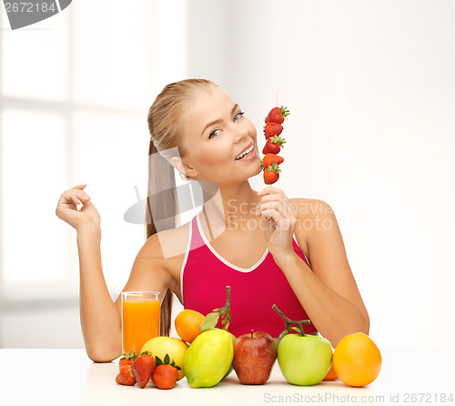 Image of smiling woman with organic food eating strawberry