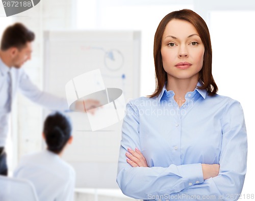 Image of smiling businesswoman with crossed arms at office