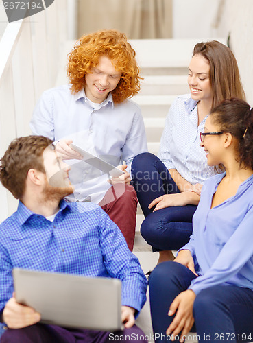 Image of team with laptop and tablet pc on staircase