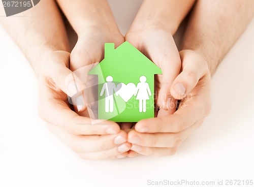 Image of hands holding green house with family