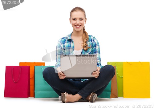 Image of smiling girl with laptop comuter and shopping bags
