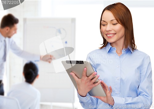 Image of smiling woman looking at tablet pc at office