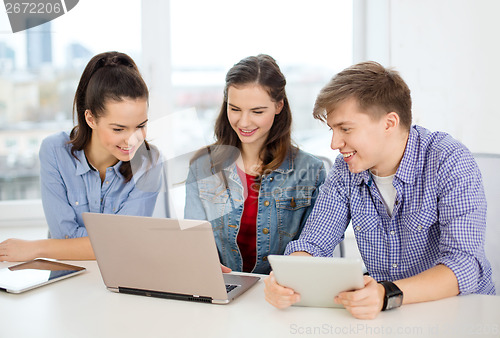 Image of three smiling students with laptop and tablet pc