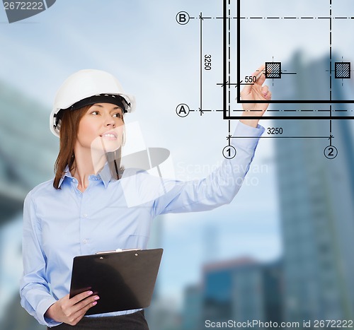 Image of smiling businesswoman in helmet with clipboard