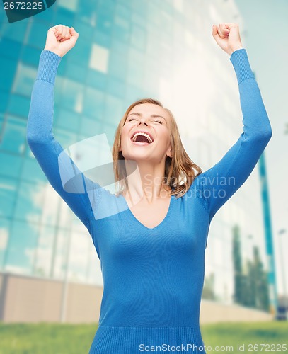 Image of laughing young woman with hands up