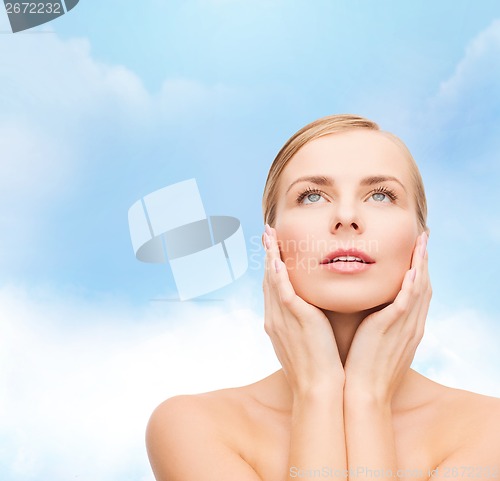 Image of beautiful woman touching her face and looking up