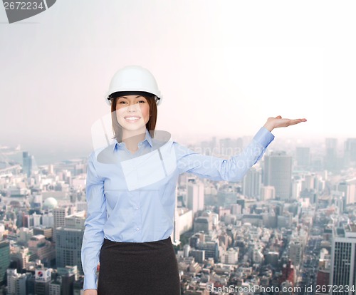 Image of businesswoman in helmet holding something on palm