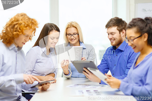 Image of smiling team with table pc and papers working