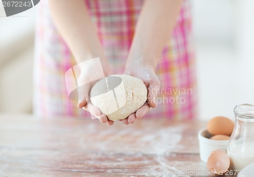 Image of close up of female hands holding bread dough