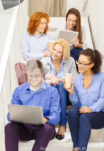 Image of team with laptop and tablet pc on staircase