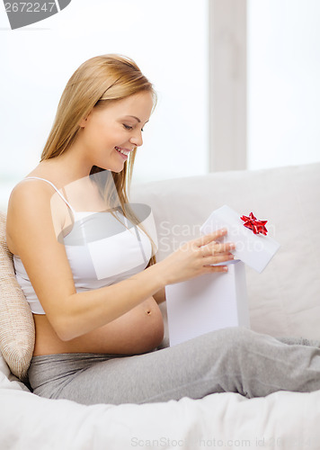 Image of smiling pregnant woman opening gift box