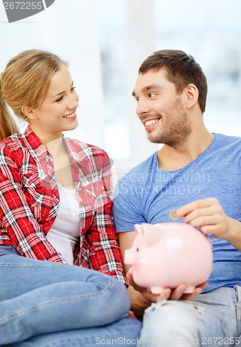 Image of smiling couple with piggybank sitting on sofa