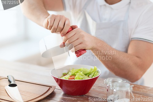 Image of close up of male hands flavouring salad in a bowl