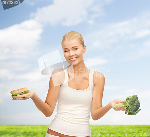 Image of smiling woman with broccoli and hamburger
