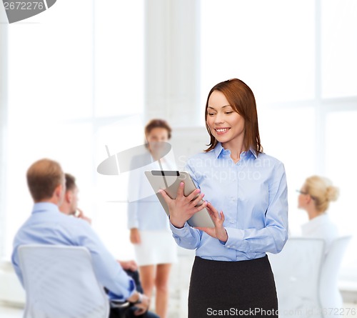 Image of smiling woman looking at tablet pc at office