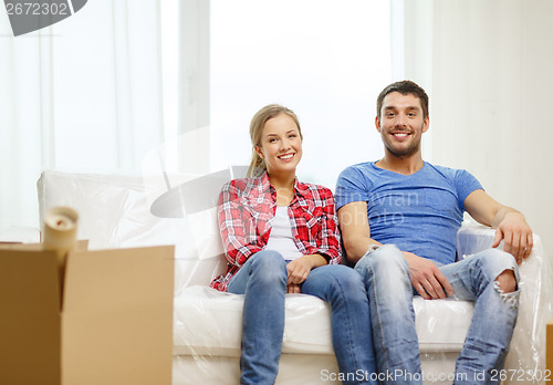 Image of smiling couple relaxing on sofa in new home