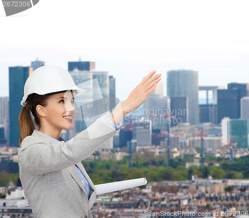 Image of smiling architect in white helmet with blueprints