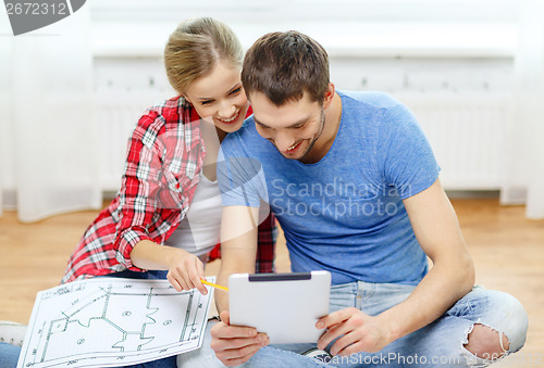 Image of smiling couple looking at tablet pc at home