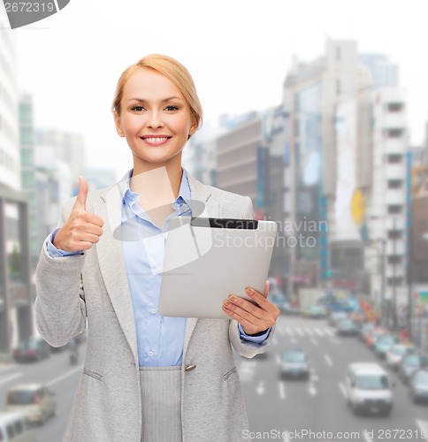 Image of smiling woman with tablet pc showing thumbs up