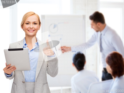 Image of smiling woman with tablet pc showing thumbs up