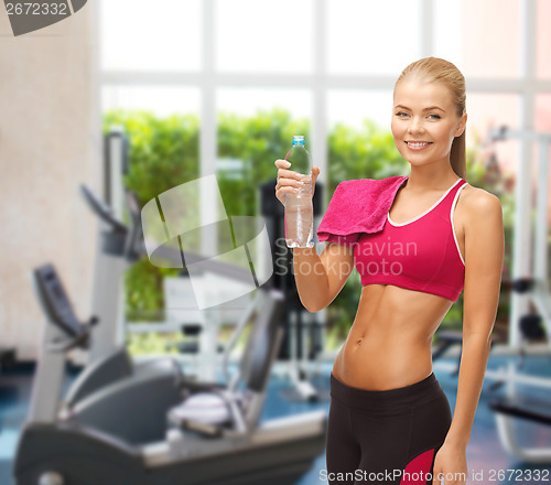 Image of smiling woman with bottle of water at gym
