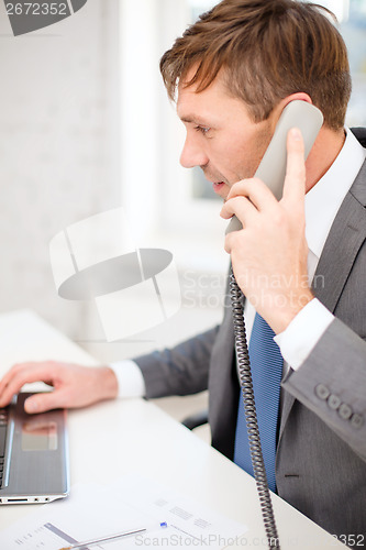 Image of businessman with laptop computer and phone