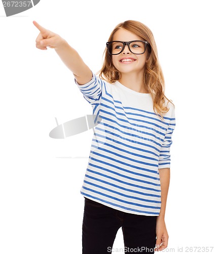 Image of cute little girl in eyeglasses pointing in the air