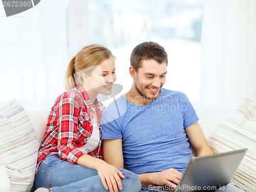 Image of smiling couple with laptop computer at home