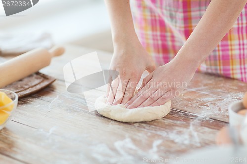 Image of close up of female hands kneading dough at home