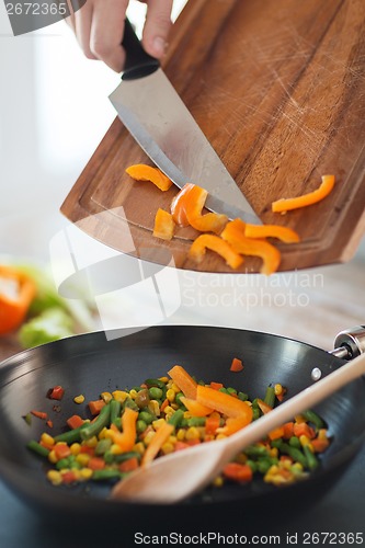 Image of close up of male hand adding peppers to wok