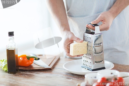 Image of close up of male hands grating cheese