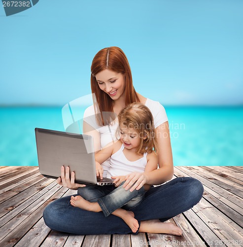 Image of happy mother with adorable little girl and laptop