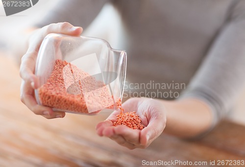 Image of close up of female emptying jar with red lentils