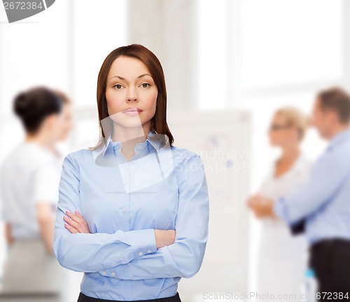 Image of smiling businesswoman with crossed arms at office